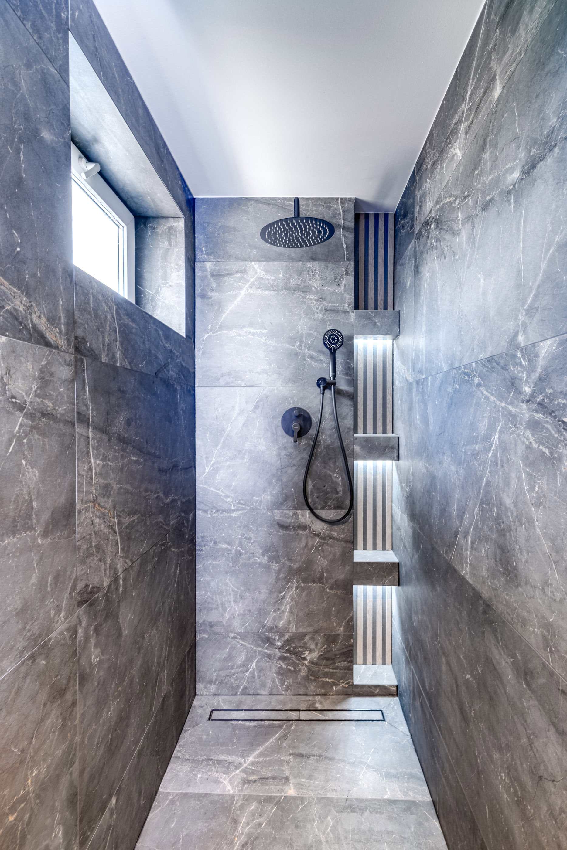 Nechybí ani prostorný walk-in sprchový kout, který krásně navazuje na zbytek koupelny a podtrhuje její čistý, moderní styl.